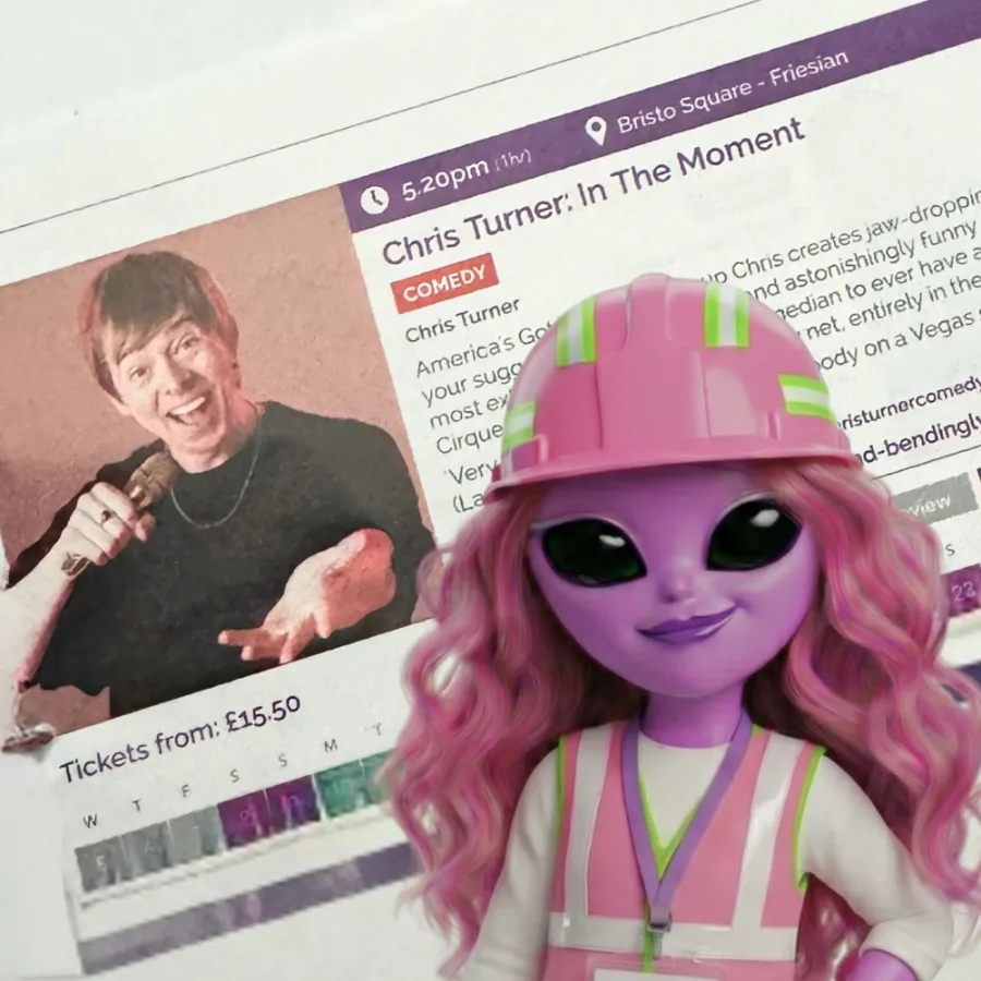 Pinkoma in a pink hard hat and hi-vis vest in front of Chris Turner's printed Fringe listing